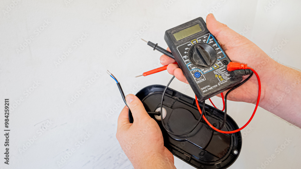 Person using a digital multimeter to check electrical wiring for ...