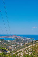 Ocean, city and landscape in nature for vacation, travel or mockup space on blue sky in Turkey. Woods, hills and buildings outdoor by sea coast for tourism location, holiday and power lines in Bodrum