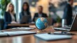 © B 7 YOU - A globe sits on a conference table in front of blurred business people.