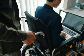 Wall Mural - Close-up of man helping businesswoman with disability while she working on laptop