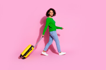 Sticker - Full body photo of attractive young woman traveler suitcase walking dressed stylish green clothes isolated on pink color background