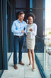 © SunriseDon/peopleimages.com - People, tablet and smile at office building for feedback, innovation and positive review. Businessman, woman and tech on balcony for connectivity, communication and research for business development