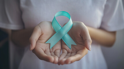 Awareness ribbon on women's hands against white T-shirt. Symbolizes cervical cancer, ovarian cancer, gynecological diseases.