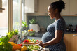 © Running opossum - Pregnant black woman is smiling while preparing a healthy meal in her kitchen
