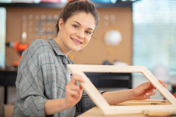 happy woman is working on wooden picture frame