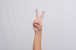 © Luqman Aditiamala - Peace symbol with hands. Hand showing two fingers, isolated on white background. People's hands are raised upwards to form a 'Peace' gesture.
