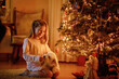 © Irina Schmidt - Beautiful little girl playing with her favourite maltese puppy near Christmas tree on Xmas Eve. Children and animals concept. Girl cares about pet at home. Happy child and dog. Magic season.
