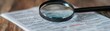 © ZpongXED - A magnifying glass over a document, emphasizing detail and focus in a wooden setting, perfect for investigative themes.