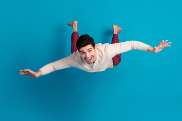 Wall Mural - Full body photo of attractive young man flying imagination playful dressed pajama sleepover good night isolated on blue color background