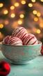 © Pixels  - Candy cane hot chocolate bombs in a decorative bowl, sitting on a mint table with a deep gold backdrop and twinkling Christmas lights, copy space, Merry Christmas background, festive candy promo