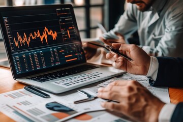 Wall Mural - Business professionals analyzing financial data on a laptop during a meeting in a modern office setting in the afternoon