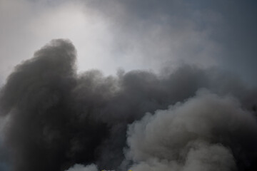 Toxic black smoke from fire against sky, burning plastic.