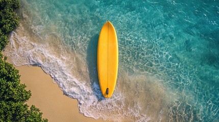 Poster - Yellow surfboard on pristine sandy beach with clear turquoise waters, aerial view. Tropical vacation and adventure concept 