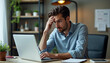 © Ali Hamza Tullah - Serious frustrated businessman touching head with hand looking at laptop pc sitting at desk in home office. Puzzled freelance employee feeling tired exhausted, chronic work stress, having headache