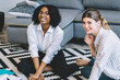 © BullRun - Portrait of happy smiling female students looking at camera while sitting on apartment floor during break from studying togetherness, cheerful hipster girls preparing to school test indoors