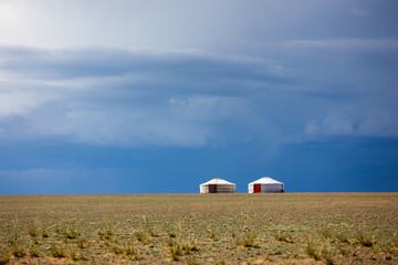 two yurts on the hill next to each other with blue sky