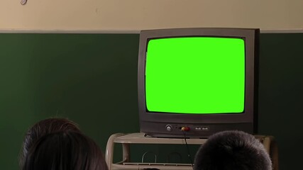 Wall Mural - old tv displaying green screen in front of the blackboard in a primary classroom - closeup - you can