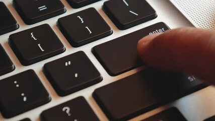 Slow motion of forefinger pressing enter key on modern laptop computer keyboard, extreme closeup macro detail, shallow DOF, one person. Sending messages, purchasing, receiving rules, executing program