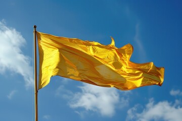 Yellow flag waving in the wind against a blue sky. National or celebratory flag concept.