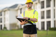 © Panacea Stock  - A man in a yellow safety vest is looking at a tablet while wearing a hard hat. He is focused on the device, possibly checking for safety information or instructions