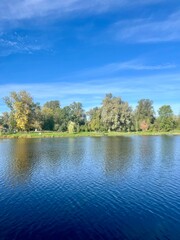 Wall Mural - Beautiful blue lake in the park, sky and trees reflection on the lake surface