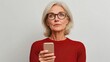 © Pannin - A middle-aged woman with a concerned expression, holding her glasses and struggling to see text on her mobile phone, highlighting the challenges of presbyopia with a plain studio background.