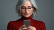 © Pannin - A middle-aged woman with reading glasses, holding a mobile phone close to her eyes in an attempt to read, demonstrating the effects of farsightedness, with a clean studio background.