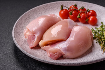 Fresh chicken fillet on a dark concrete table with spices and herbs