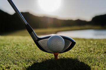 Close-up of a golf club poised to strike a ball on a lush green course. Ideal for sporting events, golf enthusiasts, capturing precision, focus, and action on the fairway.