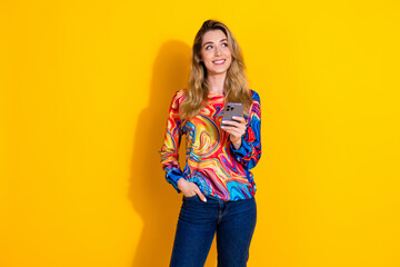 Wall Mural - Photo portrait of lovely young lady look empty space hold device dressed stylish colorful garment isolated on yellow color background