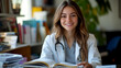 © Phatcharee - Portrait of smiling female physician with stethoscope, sitting at desk with open medical textbook, warm office lighting