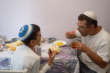 jewish family celebrating hanukkah, israel, boy in kippah, jewish holidays, yom kippur feast, table with food, honey, donuts, family holiday, religious family, family praying, Jewish woman