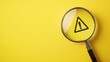 © Elchin Abilov - Attention sign exclamation mark warning sign concept A magnifying glass focuses on a hazard warning icon over a yellow background conveying the importance of paying attention to safety