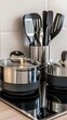 © Viktoriia Kan - Close up of stylish kitchenware highlights dark grey stone-finished pots and pans placed on an electric stove, complemented by stainless steel utensils in a neutral setting