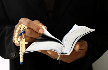 black man praying to god with crucifix and hands together Caribbean man praying on black background with people stock photos stock image	