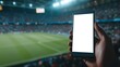 © nakarin - Person Holding Smartphone with Blank Screen at a Soccer Stadium During a Night Match