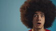 © Larissa - Surprised young man with large afro making a shocked expression, isolated against a blue background, ideal for expressive and emotional concepts.