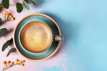 Cup of hot coffee on colorful background. Aromatic beverage with brown foam. Black coffee mug on blue surface. Morning coffee break with delicious hot drink. Enjoying fresh coffee with tasty aroma.