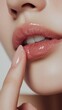 © umut hasanoglu - Close-up of a woman's glossy lips with a finger gently touching them.