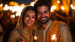 © vidkit - Indian man and woman in traditional attire, standing close and holding sparklers, smiling with bright Diwali lights