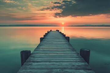 Sunset over calm lake with wooden pier extending into water, peaceful nature landscape