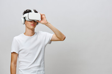 Virtual reality experience, young man wearing VR headset, isolated on gray background, engaging in immersive technology, futuristic exploration of digital environments and gaming