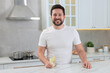 © New Africa - Happy man holding glass of water with lemon in kitchen