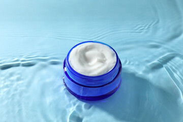 Poster - Jar with face cream in water on light blue background