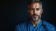 © jul_photolover - A confident male doctor in scrubs with a stethoscope, posing against a dark background in a clinical setting during the evening