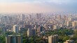 © miss irine - Aerial view of Pune city in Maharashtra, India. Skyscrapers and modern architecture dominate the skyline. Hazy smog fills the atmosphere. Trees and greenery amidst the urban landscape.