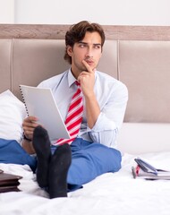 Wall Mural - Young employee working at home sitting on the bed