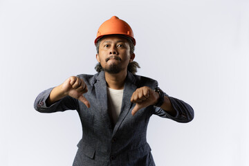 the project leader makes a gesture of dissatisfaction or disbelief by giving a thumbs dostylish asian man with orange suit and helmet on white background. construction or mining business concept photo