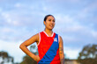 © Austockphoto - one female football player standing with hand on hip against cloudy sky
