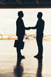 © JordaanExams/peopleimages.com - Handshake, silhouette and meeting with business people at airport for international merger, contract and deal. Headhunter recruitment, confidential and onboarding with global venture for acquisition